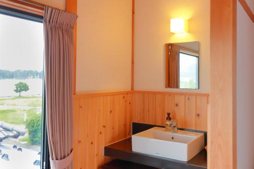 a bathroom with a sink and a mirror and a window at Jinpuso in Miyazu