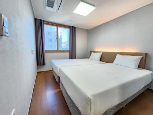 2 Betten in einem Zimmer mit 2 Fenstern in der Unterkunft Residence Hotel K Okpo in Geoje