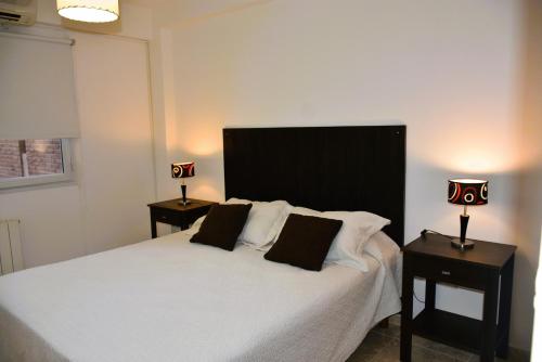 una camera da letto con un letto bianco con due tavoli e due lampade di Patagonia 55 a Neuquén