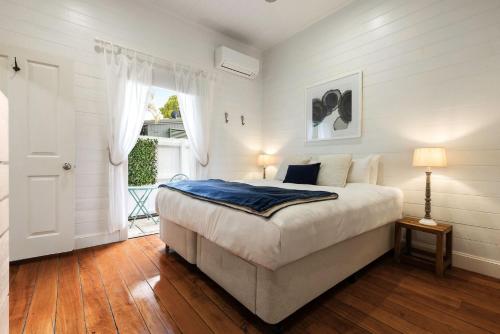 a white bedroom with a bed and a window at A Perfect Stay Aaloka Bay in Byron Bay