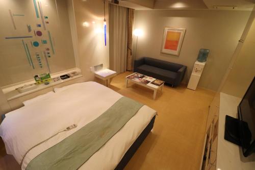 um quarto de hotel com uma cama e um sofá em ホテルシエル em Himeji