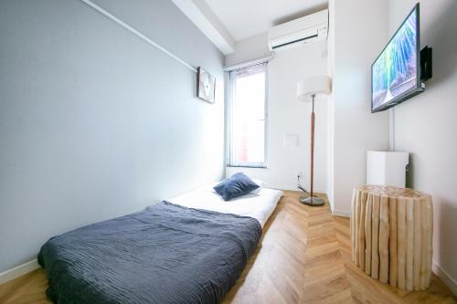 een slaapkamer met een bed en een tv aan de muur bij リアル錦糸101 in Tokyo