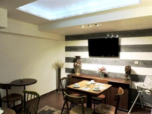 a dining room with a table and chairs and a television at Hôtel de l'Aveyron in Paris