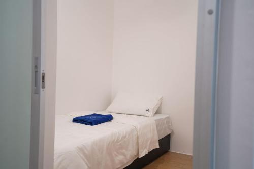 a white bed with a blue pillow on top of it at ITCC Manhattan Suites by Calvin in Donggongon