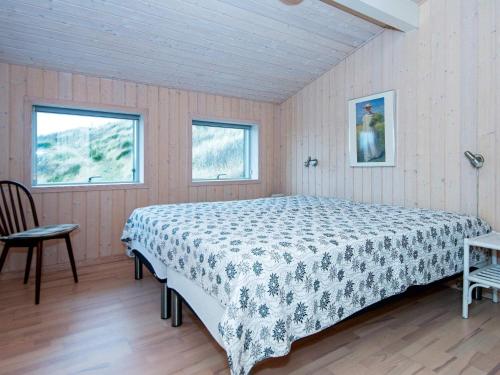 ein Schlafzimmer mit einem Bett, einem Tisch und zwei Fenstern in der Unterkunft Holiday home Henne CXXXV in Henne Strand