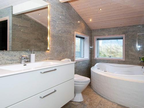 ein Badezimmer mit einer Badewanne, einem Waschbecken und einem WC in der Unterkunft Holiday home Henne CXXXV in Henne Strand