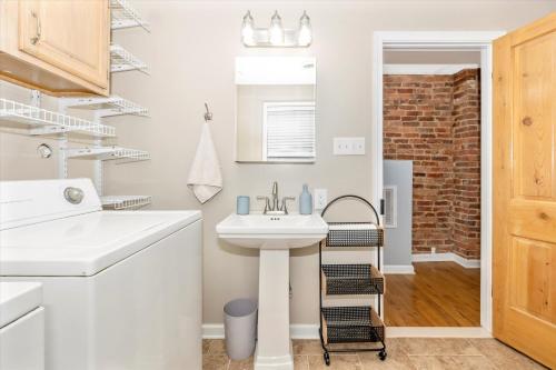 a white bathroom with a sink and a brick wall at Cozy & Inviting Townhome in Frederick