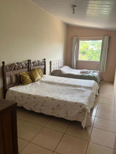 two beds in a room with a window at Kitnet ao lado do centro in Itabira