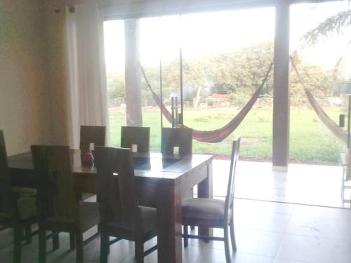 einen Esstisch mit Stühlen und ein großes Fenster in der Unterkunft Hermosa Casa de Campo en Santiago de Chiquitos in Santiago de Chiquitos