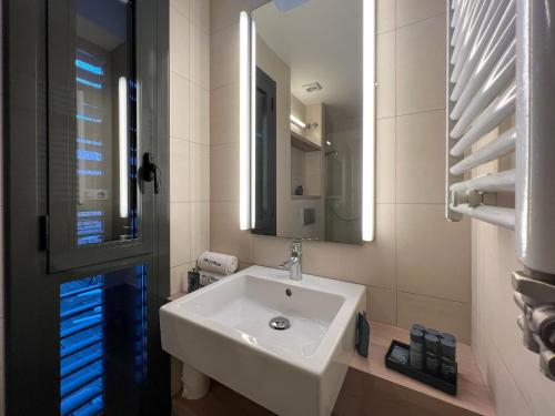 La salle de bains est pourvue d'un lavabo blanc et d'un miroir. dans l'établissement Stay U-nique Apartment Pau Claris, à Barcelone