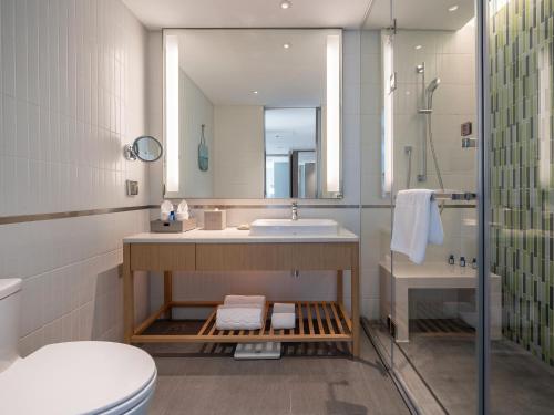 a bathroom with a sink and a toilet and a mirror at Sanya Haitang Bay Moutai Resort Classic Hotel in Sanya
