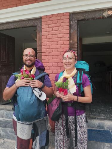 Un uomo e una donna che portano dei fiori davanti a un palazzo. di Hotel small town guest house a Bandipur