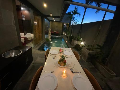a dining room with a table and a swimming pool at Bali Golden Elephant Boutique Villa in Jimbaran