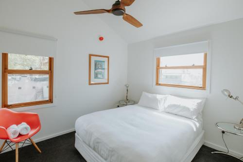 a bedroom with a white bed and a red chair at The Bronte Boutique Hotel in Morpeth