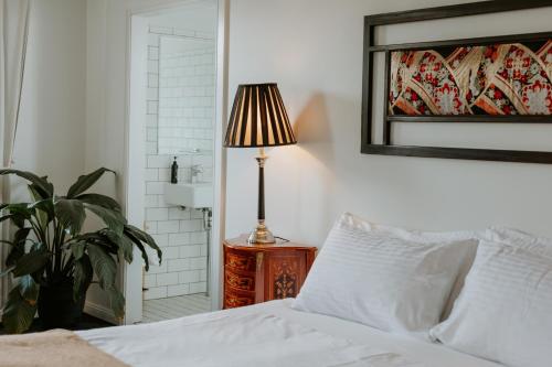a bedroom with a bed and a lamp on a night stand at The Bronte Boutique Hotel in Morpeth