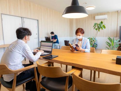 Dos personas sentadas en una mesa con un ordenador portátil en Guest House Goto Times - Vacation STAY 59196v, en Goto