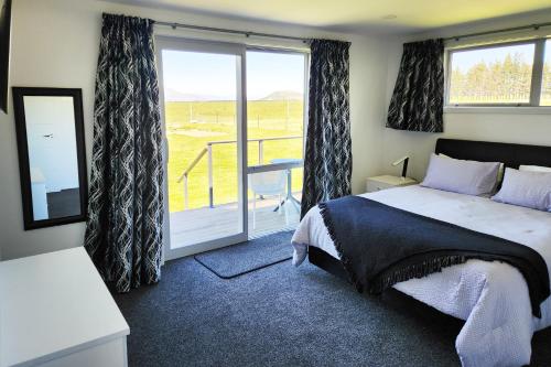 a bedroom with a bed and a sliding glass door at Glen View Escape in Twizel
