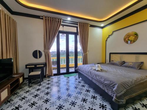 een slaapkamer met een bed, een televisie en een bureau bij Quê hương Villa (Indochine Villas Tam Chau) in Bao Loc
