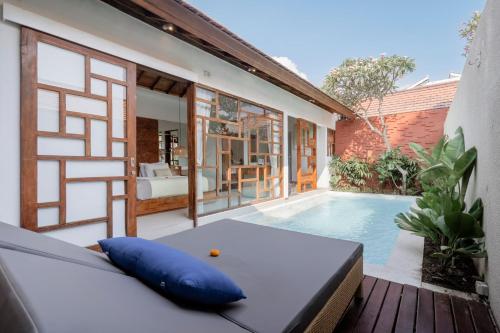 a balcony with a swimming pool and a couch at Manca Villa Canggu by Ini Vie Hospitality in Canggu
