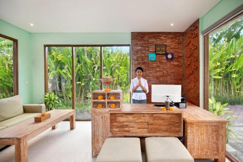 a woman standing in a living room with a table at Manca Villa Canggu by Ini Vie Hospitality in Canggu