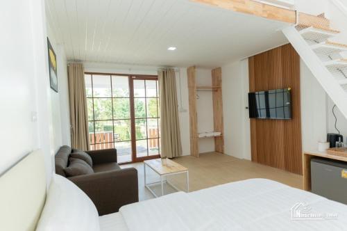 Habitación con cama, sofá y TV. en นอร์ดิกเฮ้าส์ แอนด์ คอฟฟี่หนองบัวลำภู, en Ban Huai Luk