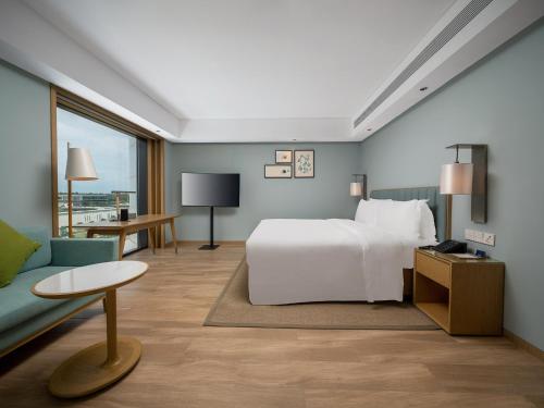 Sanya Haitang Bay Moutai Resort Classic Hotel في سانيا: غرفه فندقيه بسرير واريكه