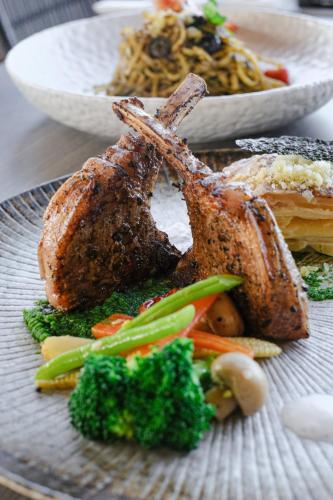 a plate of food with meat and vegetables on a table at Amartahills Hotel and Resort in Batu