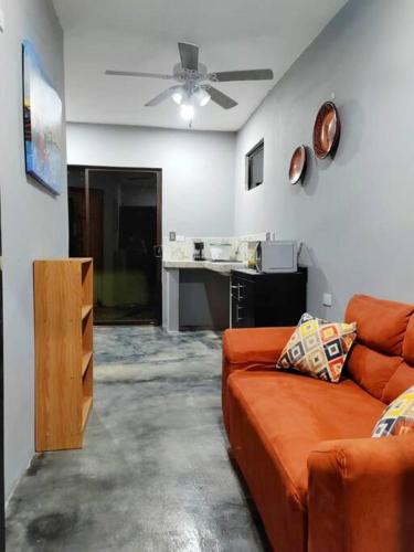 een woonkamer met een oranje bank en een plafondventilator bij Kame house. in Coronado