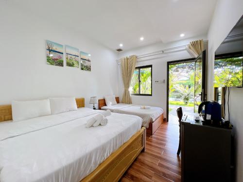 sypialnia z 2 łóżkami, telewizorem i oknami w obiekcie Rum Resort w Duong Dong
