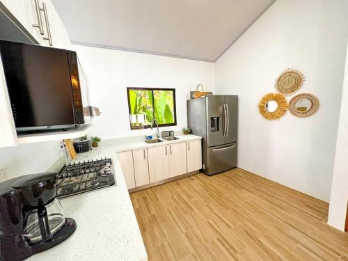 a kitchen with a stainless steel refrigerator and wooden floors at Casa Garza, con a/c y wifi in Quepos