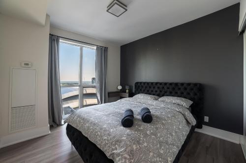 a bedroom with a bed with black walls and a window at Designer condo w/ CN Tower view & parking in Toronto