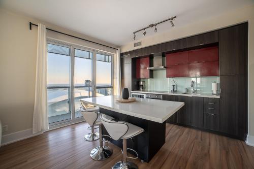 een keuken met een groot eiland met twee krukken bij Designer condo w/ CN Tower view & parking in Toronto