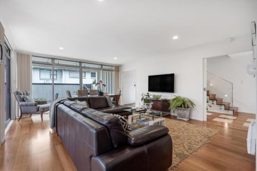 a living room with a leather couch and a television at The Bays Bed & Breakfast in Auckland