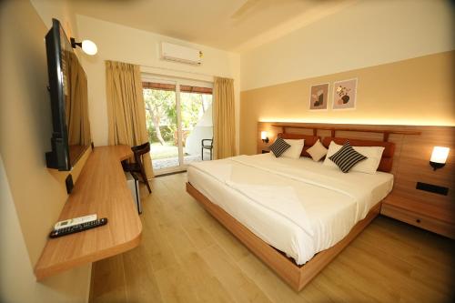 una camera da letto con un letto e una televisione di Anjuna Beach Resort ad Anjuna