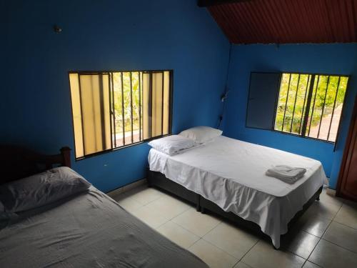 two beds in a blue room with two windows at Casa de Campo El Regalo in Norcasia