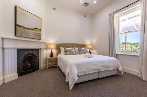 Dormitorio blanco con cama y chimenea en The Residence at Schubert Estate en Nuriootpa