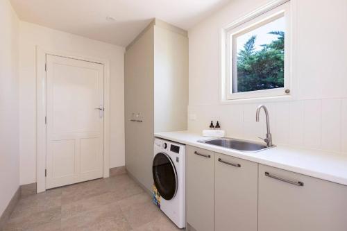 a white kitchen with a sink and a washing machine at The Residence at Schubert Estate in Nuriootpa