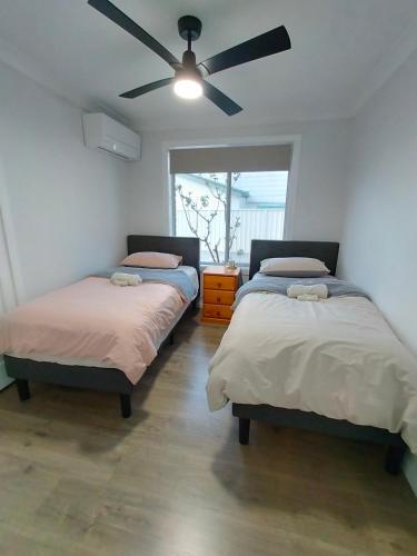 two beds in a room with a ceiling fan at 4 Bedroom, 3 bath room home in Kingswood NSW, free WIFI Internet, free parking in Kingswood