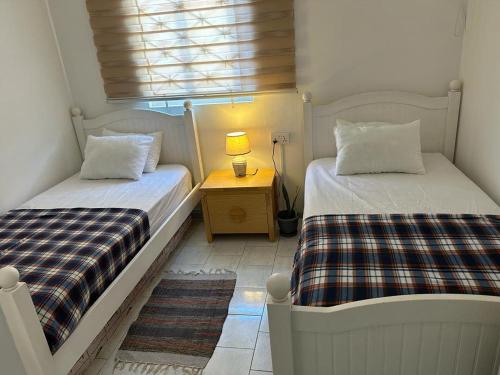 two beds in a room with a table and a window at BLEU TROPICAL in Grand Baie