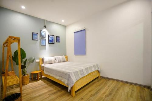 1 dormitorio con 1 cama en una pared blanca en Almor Homestay 2 Food, Bread & Coffee HaLong, en Ha Long
