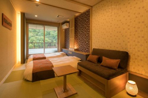 - une chambre avec un lit, un canapé et une fenêtre dans l'établissement Ryokan Fushioukaku, à Ikeda
