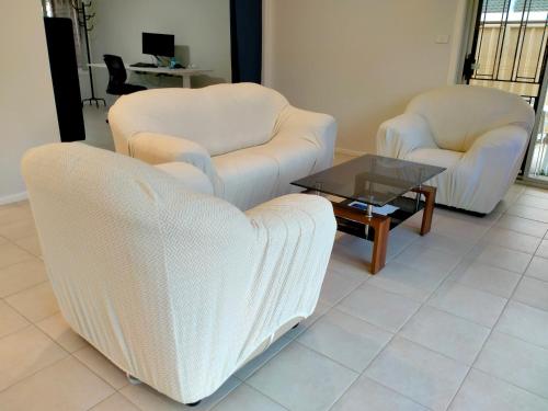 two chairs and a coffee table in a living room at 4 Bedroom, 3 bath room home in Kingswood NSW, free WIFI Internet, free parking in Kingswood