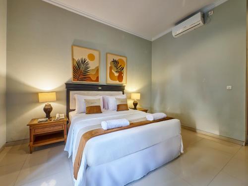 a bedroom with a large white bed and a table at U Tube Hotel in Uluwatu