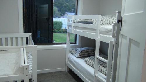 a couple of bunk beds in a room with a window at East Coast Hideaway Beach Retreat in Orford