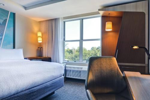 a hotel room with a bed and a desk and a window at Courtyard by Marriott Jackson Madison in Madison
