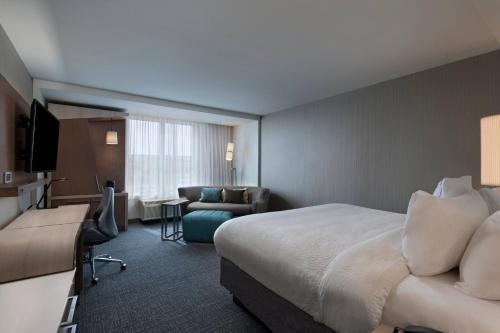 a hotel room with a bed and a living room at Courtyard by Marriott Jackson Madison in Madison
