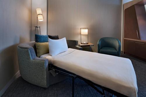 a room with a bed and a chair and a couch at Courtyard by Marriott Jackson Madison in Madison