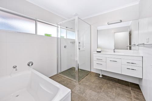 a white bathroom with a tub and a sink at Hunter Oasis in Morpeth