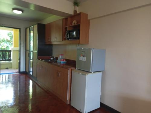 a kitchen with a white refrigerator and wooden cabinets at Apo 201-Alta Vista De Boracay in Boracay