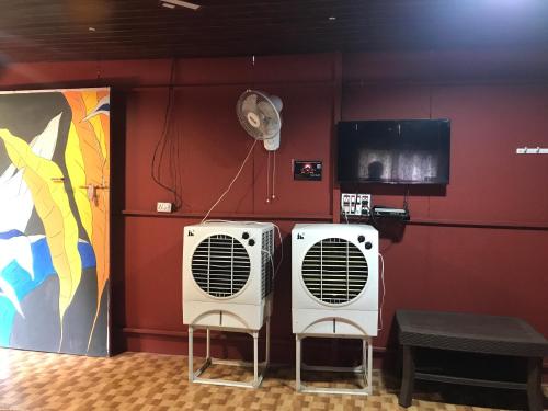 2 acondicionadores de aire blancos en una habitación con una pared roja en Ingawale farmhouse (agro tourism) en Sātāra